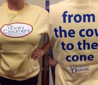 Photo of a UDairy Creamery t-shirt, yellow with the words From the Cow to the Cone on it.