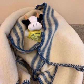 A photo of a wool baby blanket wrapped around a cow plushie.