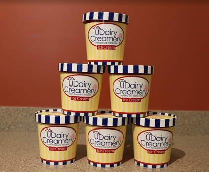 A photo of 6 pints of UDairy Creamery ice cream stacked like a pyramid.